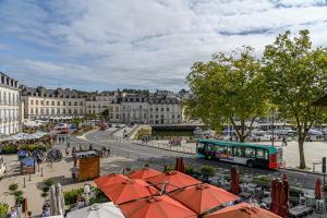a bus driving down a city street with umbrellas at Ty Mary-Ann - Duplex de 100 m² vue port in Vannes