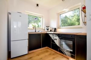 a kitchen with a white refrigerator and two windows at Domki Perła Białki z Jacuzzi in Białka Tatrzanska