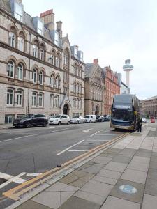 a bus is driving down a city street with buildings at Charming Apartment in Liverpool City Centre - Peaceful Sleep! in Liverpool