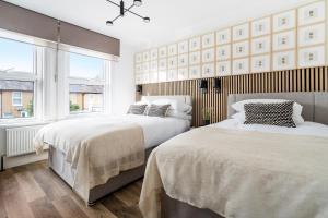 two beds in a bedroom with two windows at Newly Designed, 2br Apt, 5min from Northwood London Tube Station, NATO HQ, Ideal for Wembley, Warner Studio, Contractors in Northwood