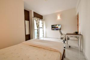 a bedroom with a bed and a desk and a tv at Namma HomeSlice, Balcony Rooms in Brookefield in Bangalore