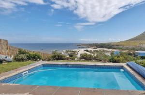 a swimming pool with a view of the ocean at Hilltop Heaven, Walk to beach, Pool, Ocean & River views in Pringle Bay