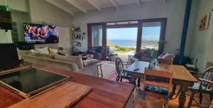a living room with a couch and a table at Hilltop Heaven, Walk to beach, Pool, Ocean & River views in Pringle Bay