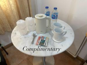 a white table with cups and water bottles on it at Surin Bay Inn in Surin Beach