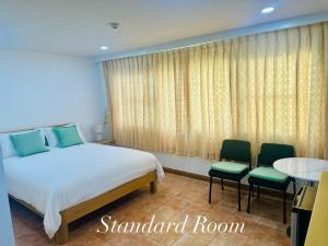 a bedroom with a bed and two chairs and a table at Surin Bay Inn in Surin Beach