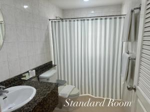 a bathroom with a shower and a toilet and a sink at Surin Bay Inn in Surin Beach
