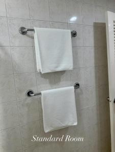 two white towels are hanging on a shower stall at Surin Bay Inn in Surin Beach