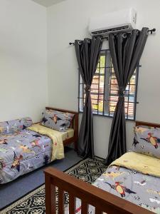 a room with two beds and a window at Kencana L&K Homestay in Air Molek