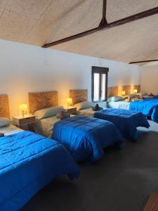 a room with four beds with blue sheets at loft el taller in Lumpiaque +25 photos