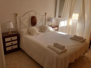 Un dormitorio con una cama blanca con dos toallas encima. en El Parque 4 dormitorios wifi playa centro, en Sanlúcar de Barrameda