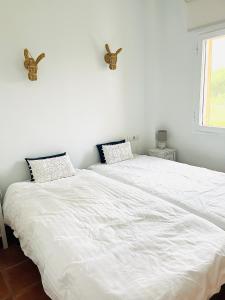 two beds in a bedroom with white sheets at Finca la Vina in Vejer de la Frontera