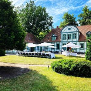 a building with tables and umbrellas in front of it at Ferienvilla Jagdschloss Friedrichsmoor in Neustadt-Glewe