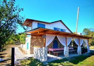 a small house with a wrap around porch at Kuća za odmor Veles in Orahovica