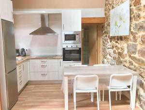 a kitchen with a table and chairs and a stone wall at La casa del Río in Pujayo