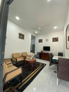 a living room with chairs and a table and a tv at Kencana L&K Homestay in Air Molek