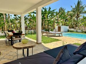 un patio al aire libre con una mesa y una piscina en Villa Totò with Private Pool ZanzibarHouses, en Gulioni