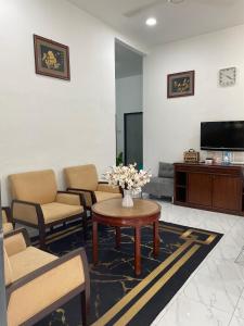 a living room with chairs and a table and a tv at Kencana L&K Homestay in Air Molek