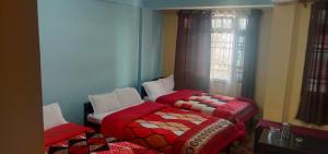 two beds sitting in a room with a window at Hotel Parichit in Namchi