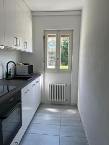 a kitchen with white cabinets and a window at Casa Enrica - bilocale a Solduno con giardino in Solduno +11 photos