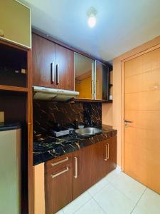 a kitchen with wooden cabinets and a sink at Younz Apartemen By Margonda Residence 2 in Pondokcina