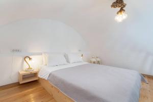 a white bedroom with a large bed with white sheets at santairini in Vourvoulos