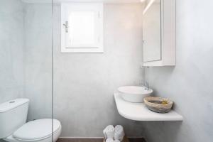 a white bathroom with a toilet and a sink at santairini in Vourvoulos