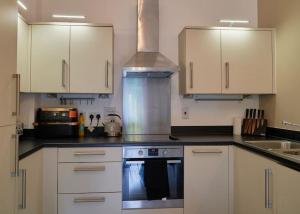 a kitchen with white cabinets and a stove top oven at Spacious Two Bedroom Hideaway in Wokingham with En Suite, Free Wi Fi and Parking, Sleeps Four in Wokingham