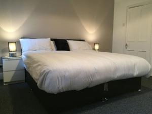a bedroom with a large bed with two lamps at Samuel Place by SG of Crewe - 5 Beds, 4 Bedrooms, 2 Bath in Crewe