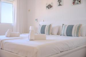 un letto bianco con cuscini bianchi sopra di Vistalmar, Duplex en Costa Adeje ad Adeje