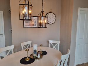 a dining room with a white table and a clock at Ferienwohnungen Springer in Schönefeld OT Großziethen div Apartments für bis zu 6 Personen in Schönefeld