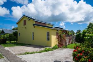 a yellow house with a fence in a yard at Villa Muscade - Maison avec piscine partagée in Saint-François
