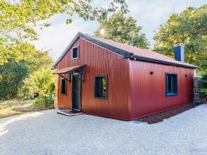 um barracão vermelho com uma porta preta na entrada da garagem em Quintinha do Varoso - Little Red Cottage House em São Pedro do Sul