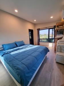 a bedroom with a large bed with blue sheets and a window at Lan Nam Ob Duen ลานน้ำโอบเดือน in Si Khio +20 photos