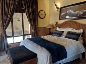 a bedroom with a large bed and a clock on the wall at Assegai Lodge in Moheme