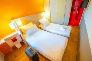 een kleine kamer met 2 bedden en een koffer bij Premiere Classe Auxerre in Monéteau