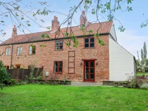 an old brick house with a red door at Woodpit Cottage in Nottingham