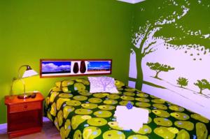 ヴィラ・ノヴァ・デ・ミルフォンテスにあるCASAZUL Milfontesの緑のベッドルーム(ベッド1台付)と木の壁画