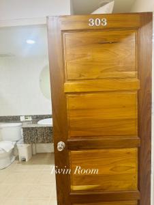 a wooden door in a bathroom with a toilet at Surin Bay Inn in Surin Beach