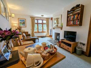 a living room with a table and a tv at Gardener’s Cottage Martinhoe in Martinhoe