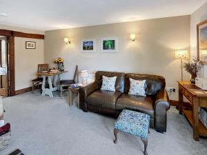 a living room with a leather couch and a table at Gardener’s Cottage Martinhoe in Martinhoe +23 photos