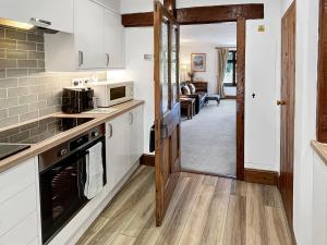 a kitchen with white appliances and a living room at Gardener’s Cottage Martinhoe in Martinhoe
