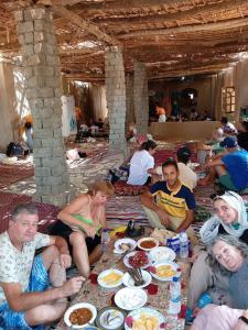 a group of people sitting around a table with food at Explore the beauty of the White Desert in Mandīshah
