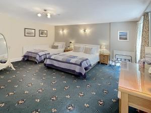 een slaapkamer met 2 bedden en een tafel bij Gamekeeper’s Cottage Martinhoe in Martinhoe