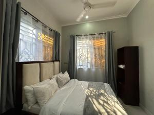 a bedroom with a bed and two windows at Amazing home stays 9 in Dar es Salaam