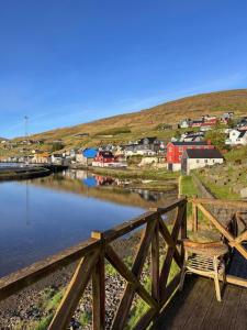 a wooden bridge over a body of water with a town at Cottage by the waterfront in Vestmanna