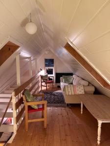 une chambre mansardée avec des escaliers, un canapé et des chaises dans l'établissement Cottage by the waterfront, à Vestmanna 24 autres photos