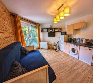 a living room with a blue couch and a kitchen at Andemu Studio cabine 2 à 4 personnes Barèges in Barèges
