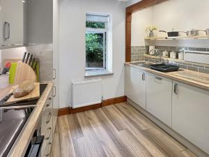 a kitchen with white cabinets and a wooden floor at Chauffeur’s Cottage Martinhoe in Martinhoe +24 photos