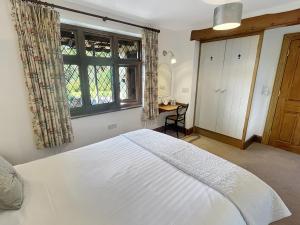 a bedroom with a large white bed and a window at Chauffeur’s Cottage Martinhoe in Martinhoe