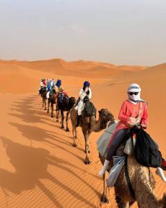 梅尔祖卡Desert Magic Camp的一群人骑着骆驼在沙漠中